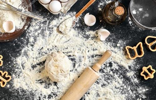 Cooking dough for cookies, butter, eggs, cooking equipment, flour on a black table. Top view with copy space, mockup for menu, recipe or culinary classes. Baking background.